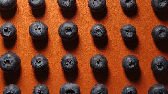 俯视图多莉拍摄的新鲜蓝莓行在橙色的背景阴影效果