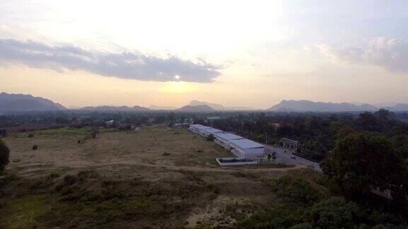 鸟瞰图的偏远村庄在日落与美丽的山背景飞走的镜头
