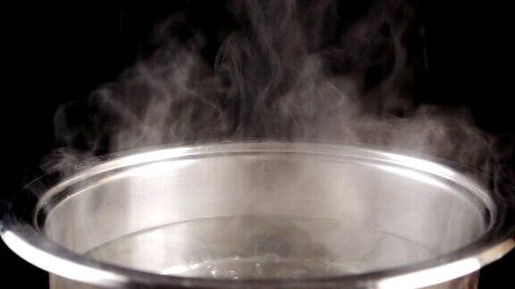 开水在黑色背景的钢锅上慢动作