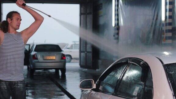 一名男子用高压清洗机喷水清洗他的汽车洗车自助服务高加索人