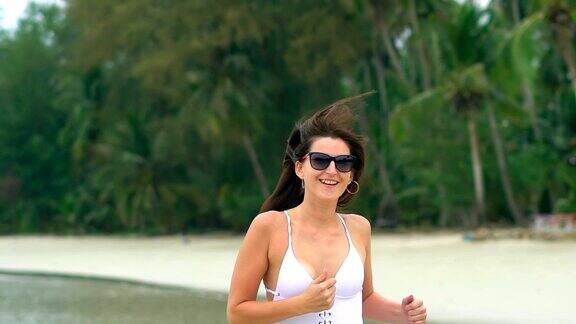 快乐的年轻女子在热带海滩上奔跑慢动作