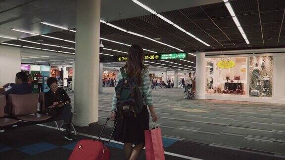带着红色行李的女乘客在机场候机楼行走