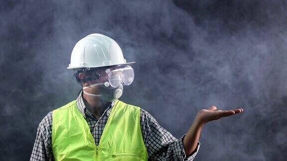肖像亚洲工人戴着安全防护装备、护目镜、面罩、帽子、背心在危险的暗室吸烟
