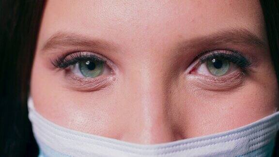 一个女人的眼睛上的特写戴着医用口罩看着相机