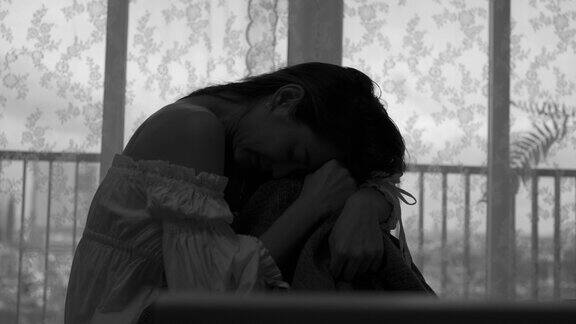 沮丧的年轻美丽的亚洲女人独自坐在公寓卧室的床上哭泣和尖叫孤独悲伤的女孩想起悲伤烦恼消极情绪与心理健康