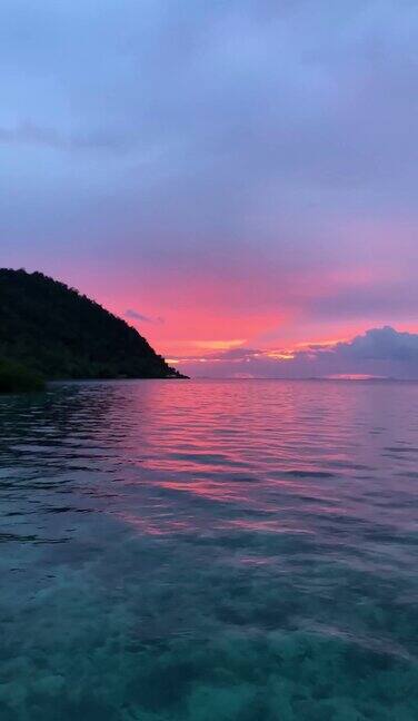 美丽的日落在海洋与野生热带岛屿在拉贾安帕印度尼西亚巴布亚岛水面日出倒影的垂直视频