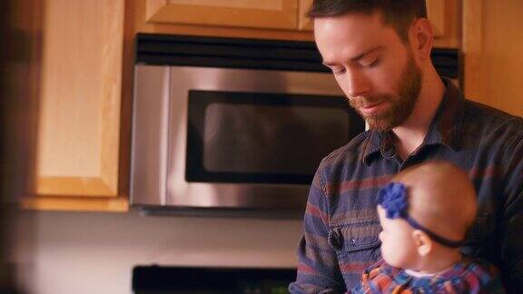 一位年轻的父亲在厨房里抱着他的孩子并和他说话