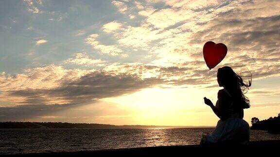 日落时分海边一个可爱的女人拿着红气球