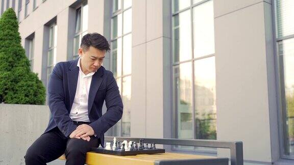 年轻的亚洲商人在长凳上下棋