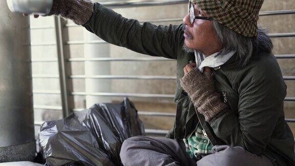 倾斜:无家可归的人在人行道上拿着乞讨的碗