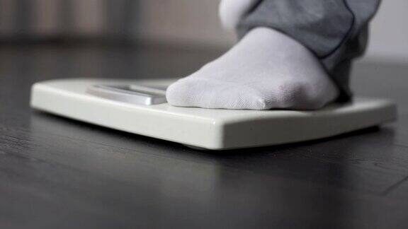 懒惰肥胖的男性踩在浴室秤上控制体重和节食