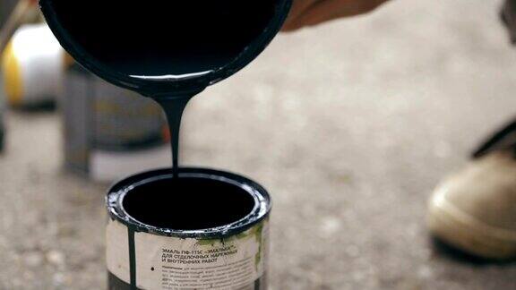 艺术家把一种黑色颜料从一个罐子倒到另一个罐子里