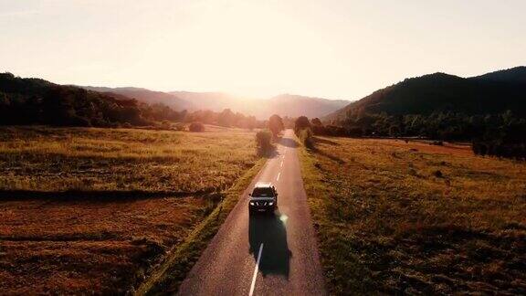 汽车行驶在空旷的乡间小路上进入了金色的夏日夕阳