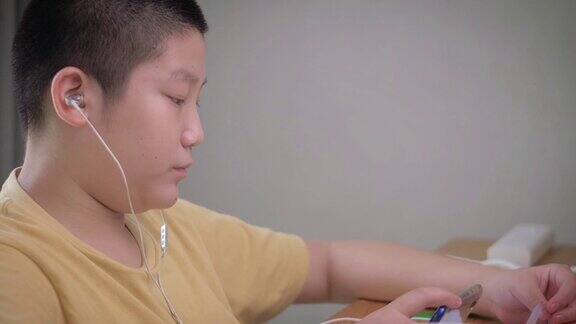 亚洲男孩在隔离期间用智能手机在线学习