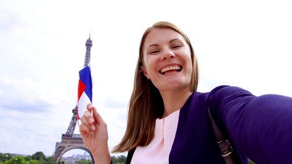 在埃菲尔铁塔附近举着法国国旗自拍的女人微笑的女游客在欧洲旅行
