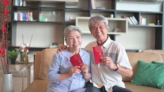 过年的老两口爷爷奶奶在客厅拿着红包看镜头