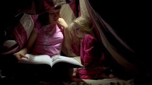 妈妈和女儿晚上在帐篷里用手电筒看书