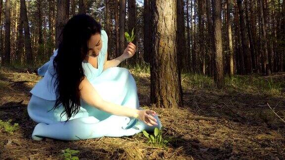 穿着蓝色衣服的漂亮女人在森林里采摘花草