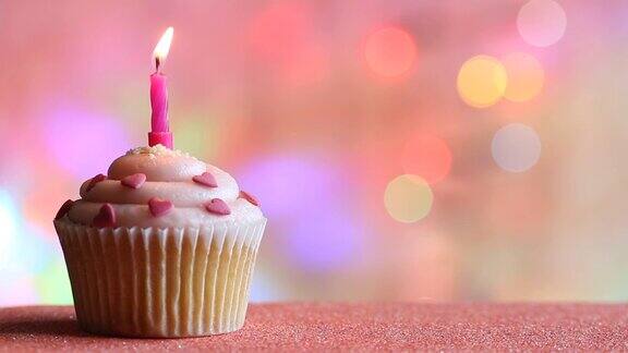 生日纸杯蛋糕和蜡烛上彩色散焦背景派对