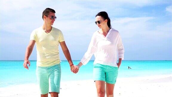 一对年轻夫妇在白色的海滩上度过暑假幸福的一家人享受他们的蜜月慢动作视频