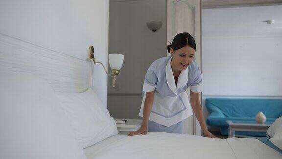 快乐的女人在酒店工作整理床铺为另一位客人准备房间