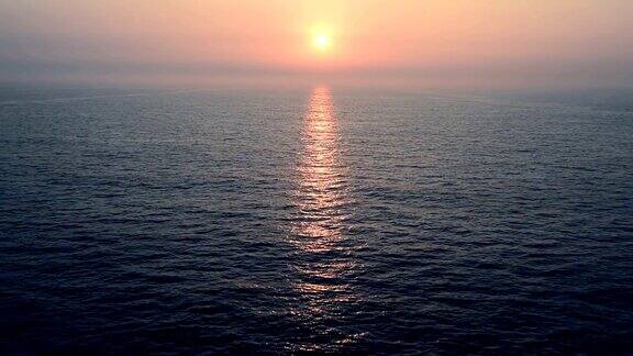 在平静的海面上从移动的巡洋舰的开放甲板上看到日落和日出