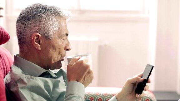 可爱的男人喝着咖啡在手机上打字:智能手机移动网络电话