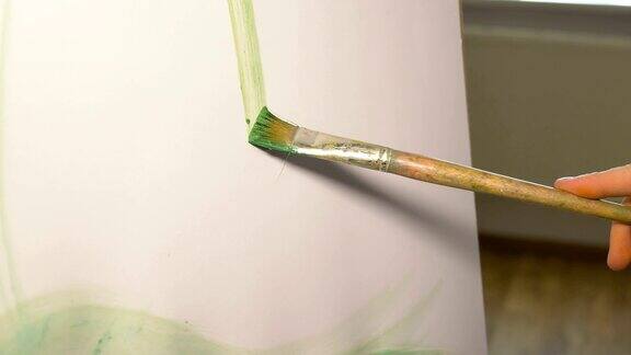 艺术家用画笔在画布上画一条绿色颜料的垂直线有创造力和不寻常的人的休闲