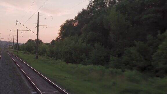 窗外的景色高速列车上美丽的自然景观野外和森林铁路轨道傍晚日落在夏天的背景交通、旅游、铁路、通讯理念