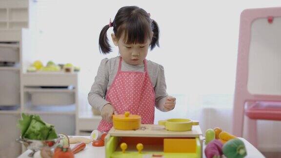 蹒跚学步的小女孩假装玩准备食物的游戏