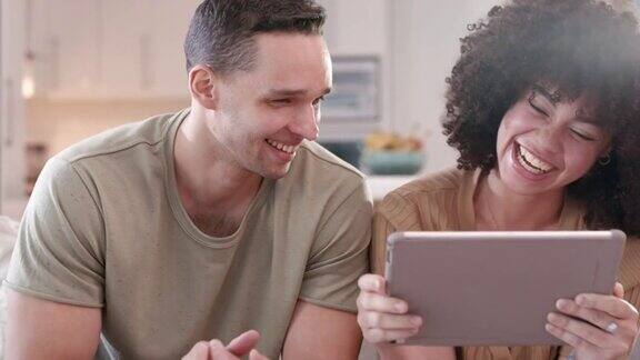 4k的视频片段一对年轻夫妇一边看电子平板电脑上的东西一边大笑
