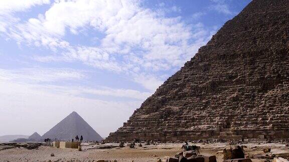 埃及吉萨金字塔我们可以看到云朵在联合国教科文组织分类的纪念碑上方埃及人在金字塔前行走