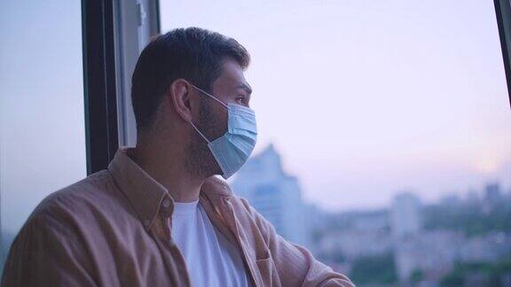 中年男子戴着防护口罩透过窗户看疫情安全