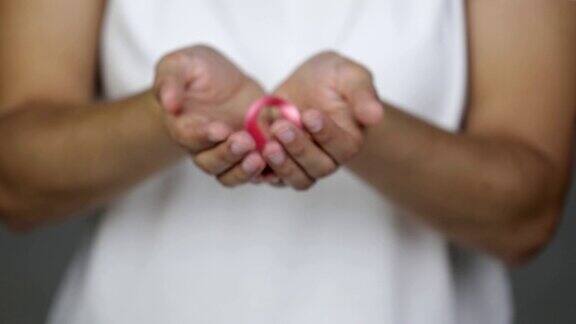 一名妇女向镜头展示了一条粉色的乳腺癌意识丝带