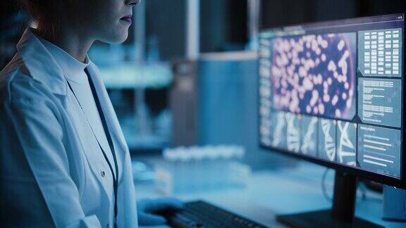医学研究实验室:女性科学家在计算机上工作的肖像分析DNA病毒医学、生物技术、疫苗开发先进科学实验室深蓝色提升镜头