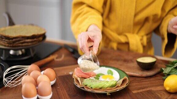 女人用鸡蛋、鳄梨和鱼做早餐
