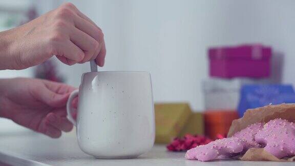 早上一个女人在一个白色的大杯子里搅拌热咖啡或茶