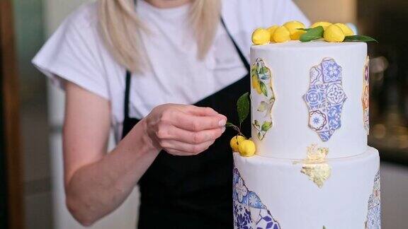满意的家庭主妇把绿叶放在两层蛋糕上的黄柠檬旁边