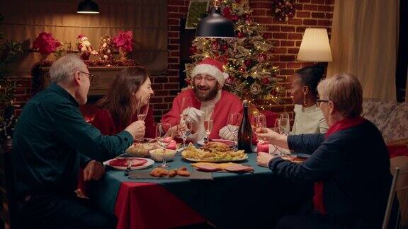 傻乎乎的圣诞老人看起来像在圣诞晚餐上一边举杯一边和家人聊天的人