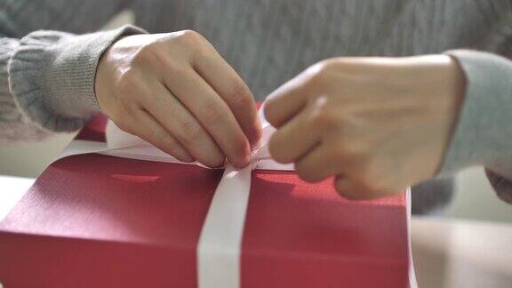 礼物包装女人为圣诞节活动系一个白色丝带蝴蝶结