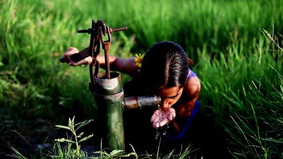 小女孩在绿色的田野边喝水