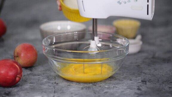 厨师将生鸡蛋和糖放在一个碗里用搅拌机搅拌