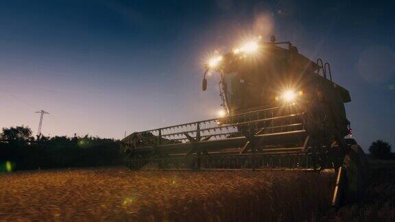 收割机晚上在农田上用前灯联合收割小麦