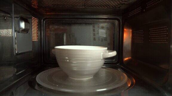 一个装有食物的陶瓷碗在微波炉中旋转加热