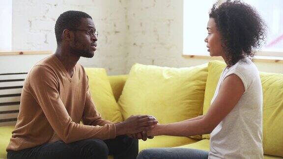 年轻的非洲裔美国人丈夫牵着妻子的手道歉