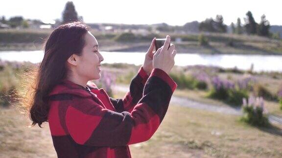 年轻的亚洲女子用智能手机拍摄美丽的景色