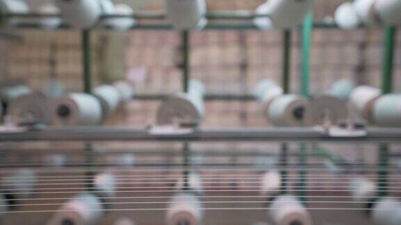 纺织厂工业整经机筒子架上的白色纱线轴