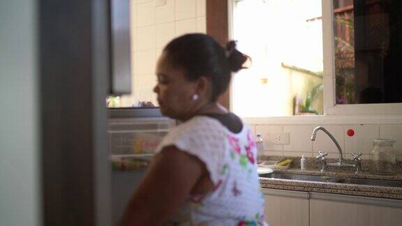 成熟的女人从家里的冰箱里拿沙拉碗