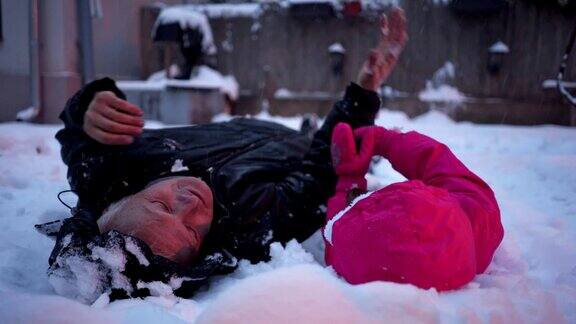 可爱的四岁小女孩享受与爷爷一起玩雪的时光
