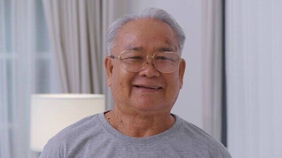 亚洲年长的白发老人在家里看着照相机快乐善良的老人在一个好心情微笑快乐的长者成熟的祖父带着牙齿的微笑在家里或退休的房子高级的肖像